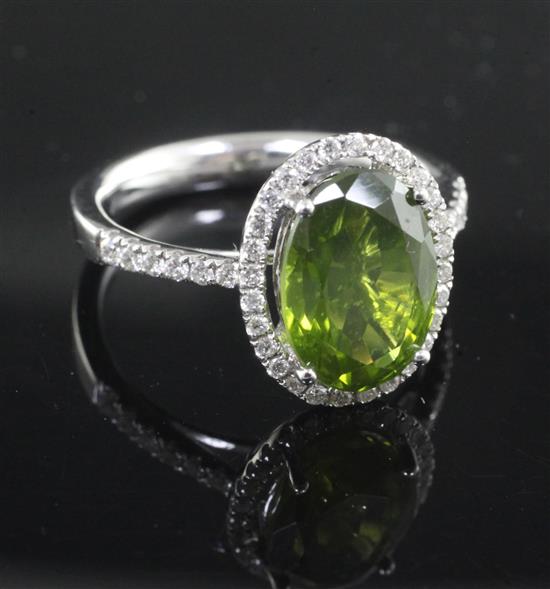 A modern 18ct white gold, green tourmaline and diamond oval cluster ring, size O.